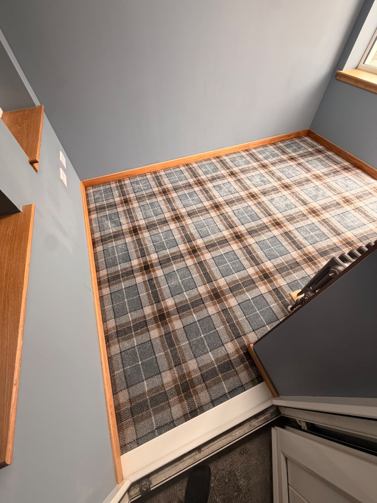 Tartan carpet fitted in a room with grey-blue walls and oak skirting